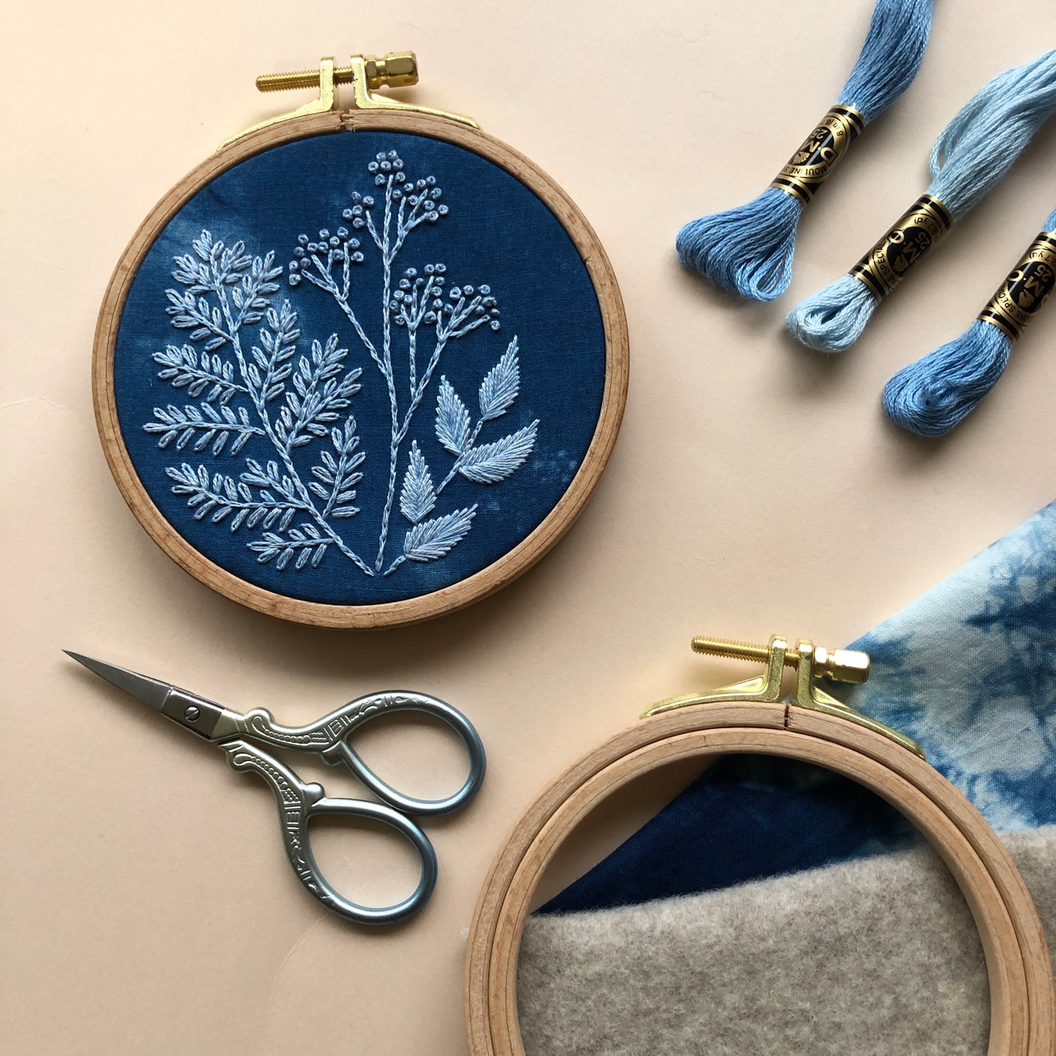 Cyanotype botanicals beginner friendly DIY embroidery kit finished embroidery within the hoop. Scissors and thread are pictured on either side of the hoop.