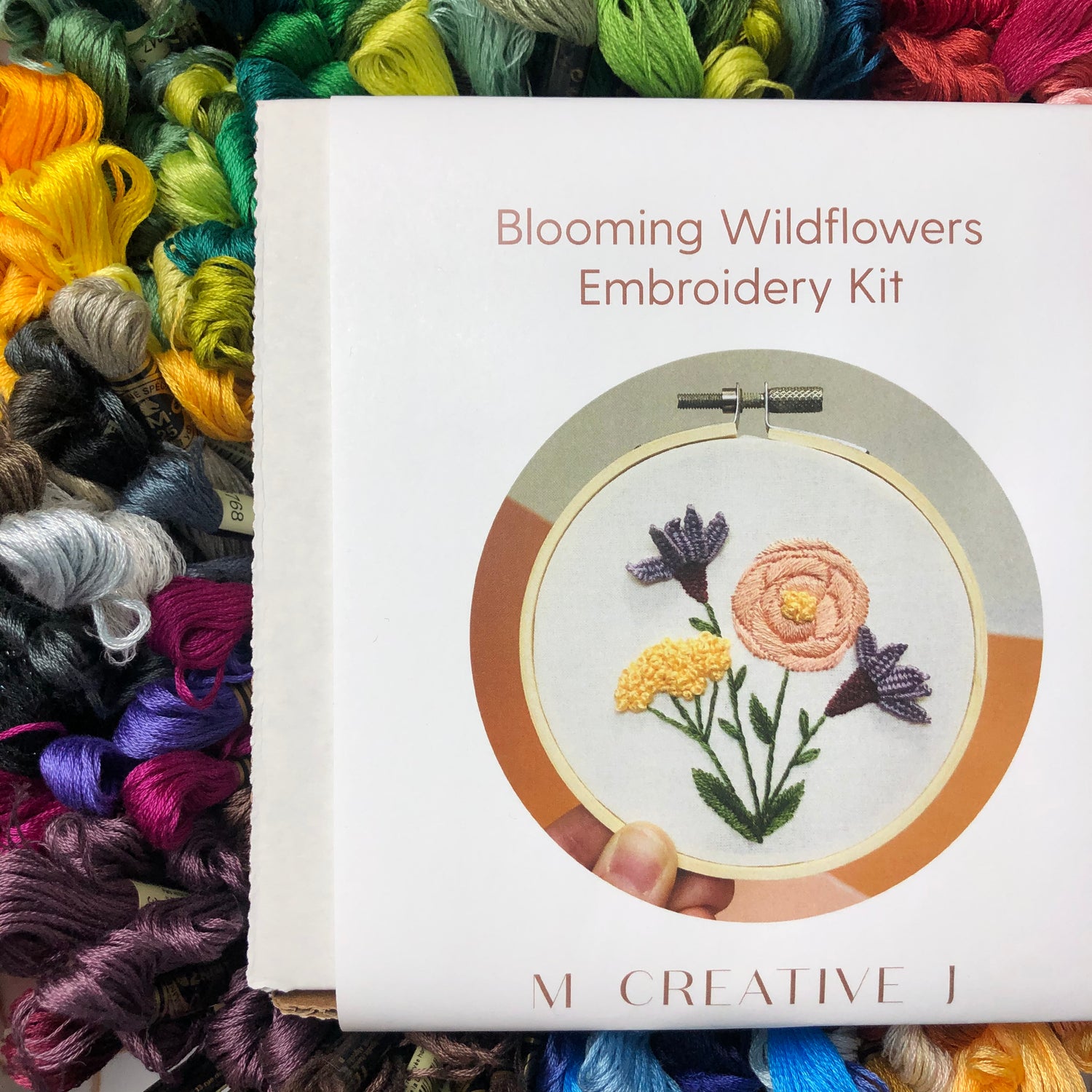 Blooming Wildflowers intermediate embroidery kit box sitting on skeins of thread