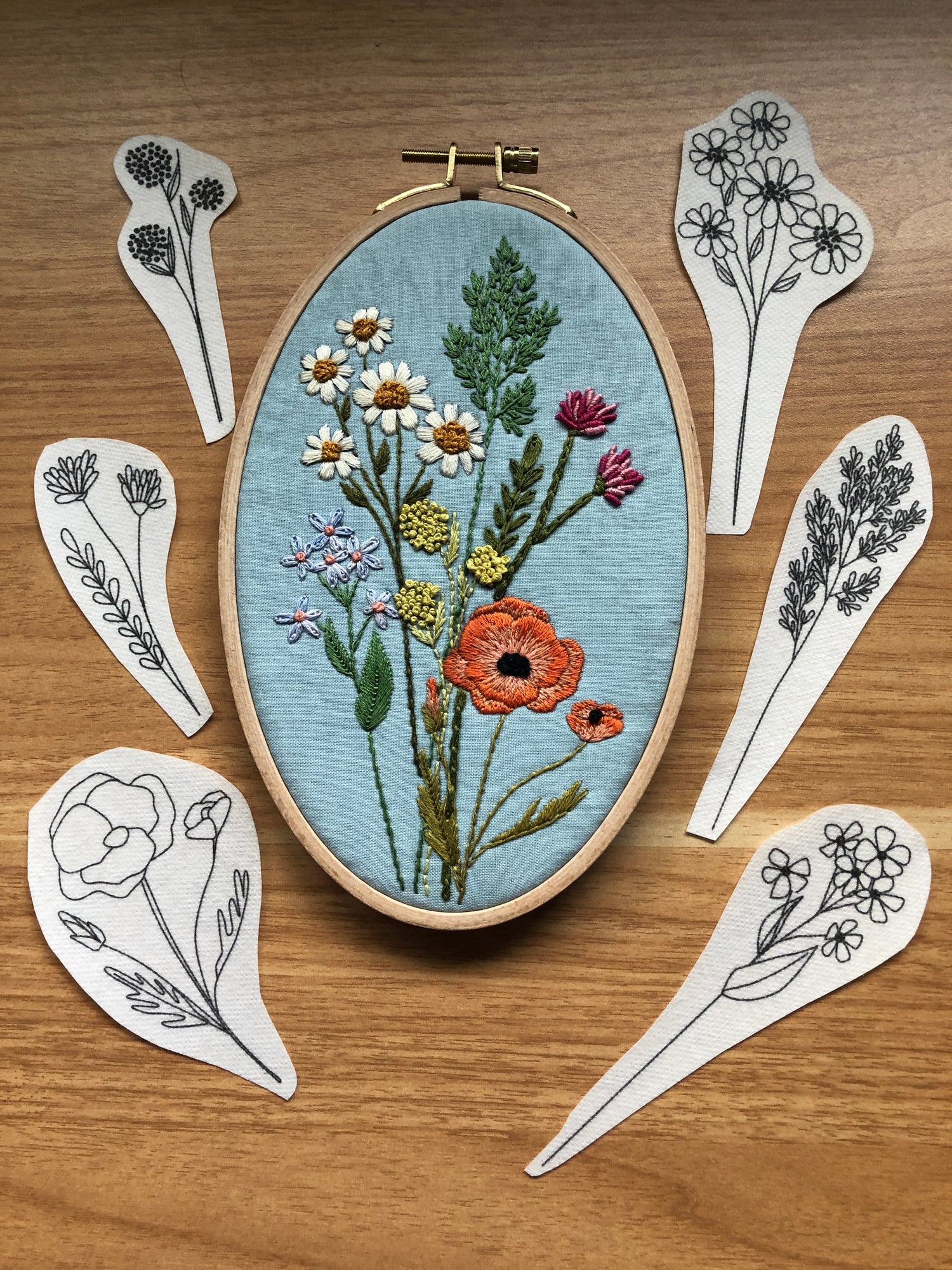 Completed embroidery design using wildflower stems stick and stitch embroidery pattern kit. Includes the 6 peel, stick, and stick designs around the completed project.
