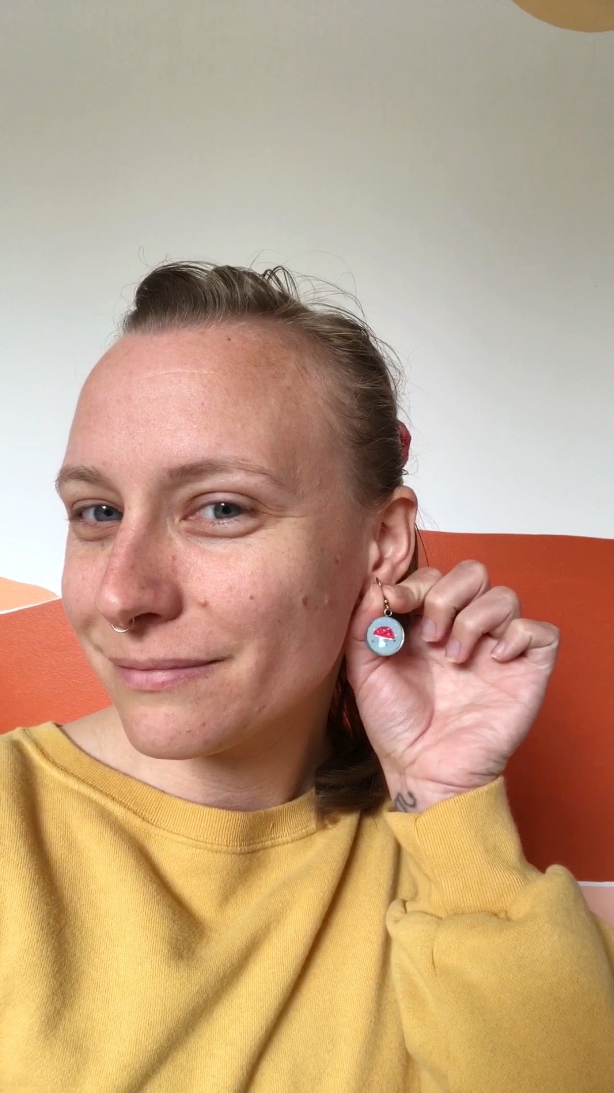 A mushroom embroidered earring from the beginner earring kit worn by Melissa